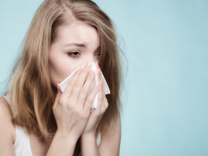 Flu cold or allergy symptom. Sick woman girl sneezing in tissue on blue. Health care.